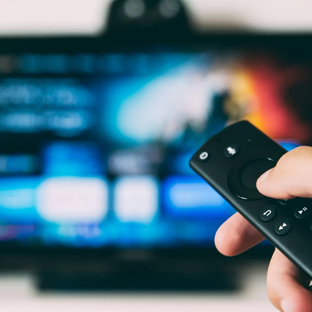 Lumen Cast 4K streaming stick controlled by its voice remote in front of a TV