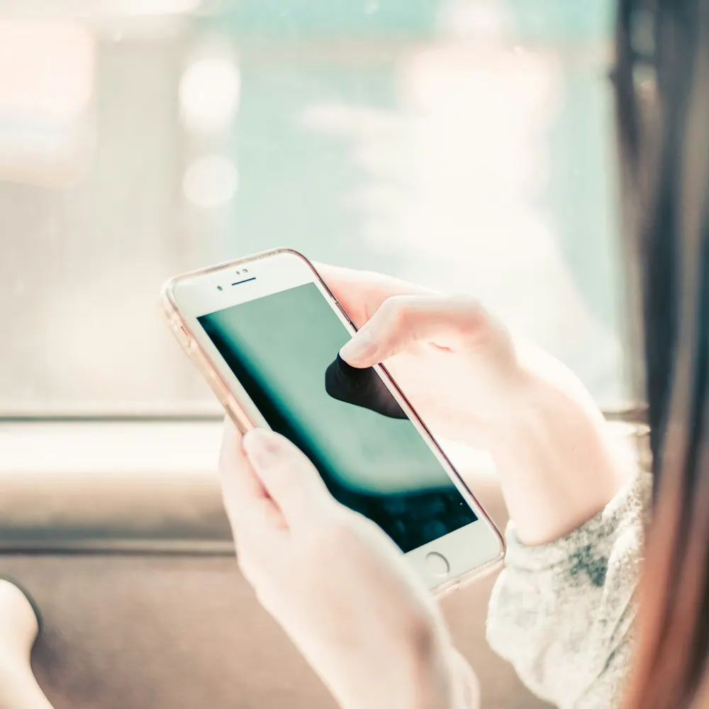 Hands holding a smartphone fitted with a Nimbus Guard tempered glass screen protector